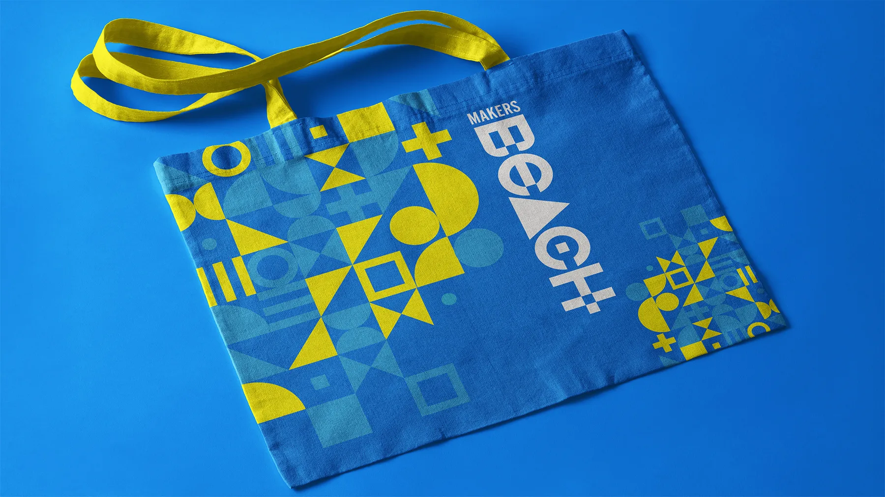 Blue Makers Beach tote bag printed with the triangle pattern and wordmark